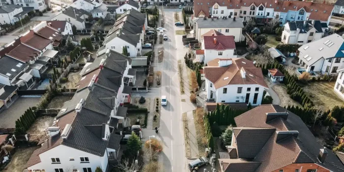 Acheteur regardant une maison en brique rénovée dans une commune résidentielle proche d'une ville