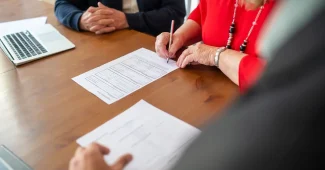 Mains tenant des documents d'achat immobilier et procès-verbaux d'assemblée générale sur un bureau