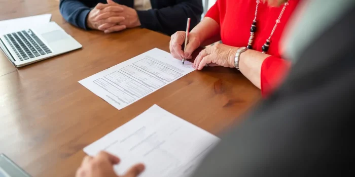 Mains tenant des documents d'achat immobilier et procès-verbaux d'assemblée générale sur un bureau