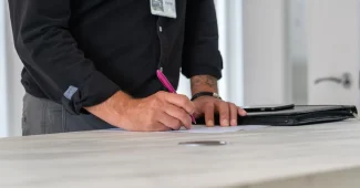 Mains signant un acte notarié avec contrat immobilier et clés sur un bureau