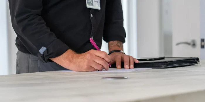 Mains signant un acte notarié avec contrat immobilier et clés sur un bureau