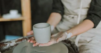 Mains tenant une tasse en céramique avec un design minimaliste et de la vapeur s'échappant