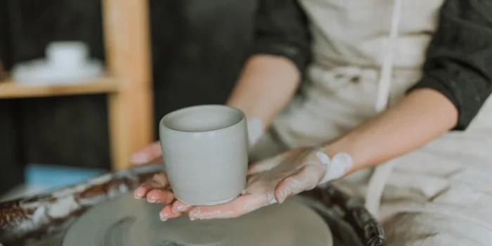 Mains tenant une tasse en céramique avec un design minimaliste et de la vapeur s'échappant