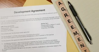 Mains signant des documents juridiques sur un bureau avec statuts d'entreprise et stylo
