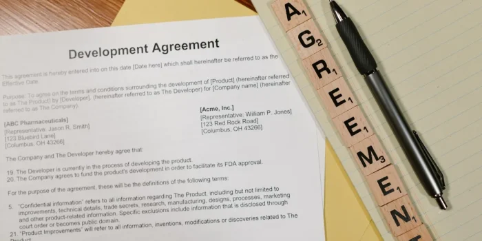 Mains signant des documents juridiques sur un bureau avec statuts d'entreprise et stylo