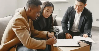 Mains tenant des documents financiers et un plan d'appartement sur un bureau avec calculatrice