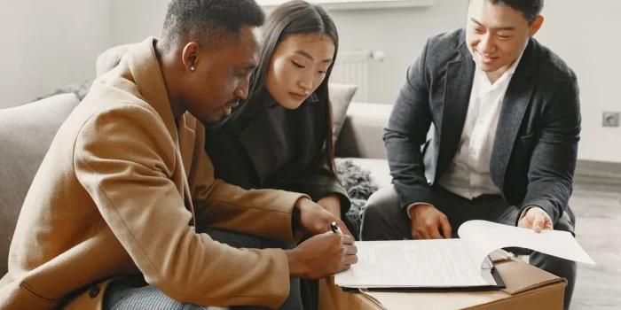 Mains tenant des documents financiers et un plan d'appartement sur un bureau avec calculatrice