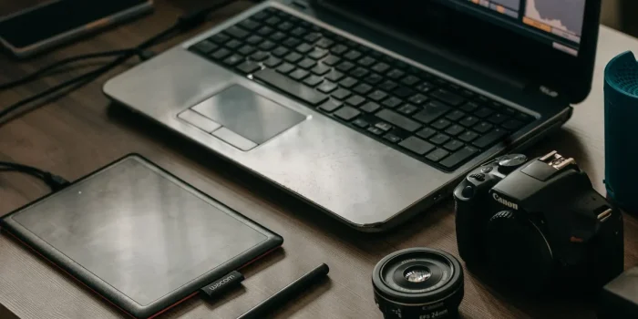 Mains d'un créateur arrangeant des produits POD sur un bureau avec ordinateur affichant une boutique en ligne
