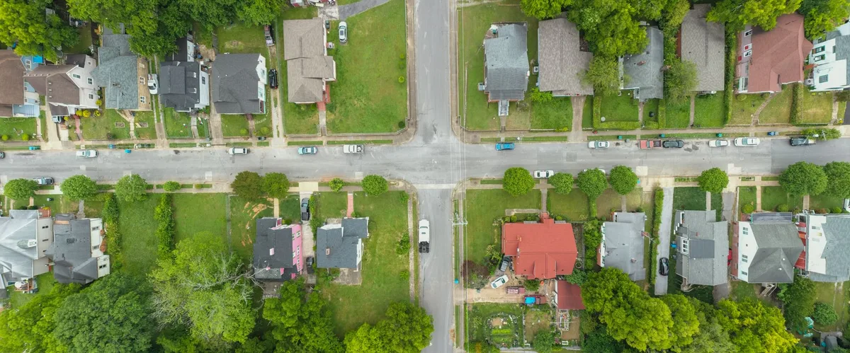 Rue résidentielle tranquille en périphérie d'une commune, maisons individuelles et jardins