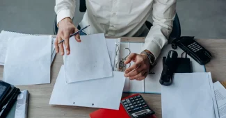 Mains tenant des documents et formulaires administratifs sur un bureau avec stylo et lunettes