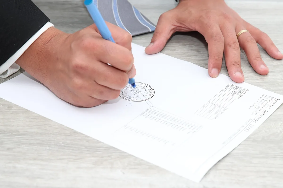 Deux personnes signant des documents avec une main tendue en arrière-plan