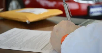 Mains sur des documents de prêt et une calculatrice sur une table en plein jour