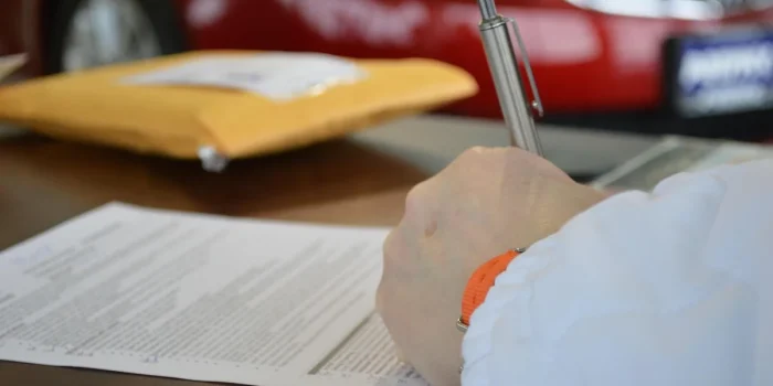 Mains sur des documents de prêt et une calculatrice sur une table en plein jour