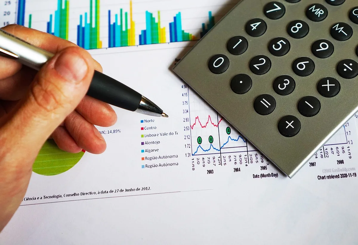 Personne calculant sa capacité d'emprunt avec une calculatrice et des documents à côté d'une fenêtre