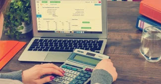 Mains anonymes triant des documents de prêt et une calculatrice sur une table baignée de lumière