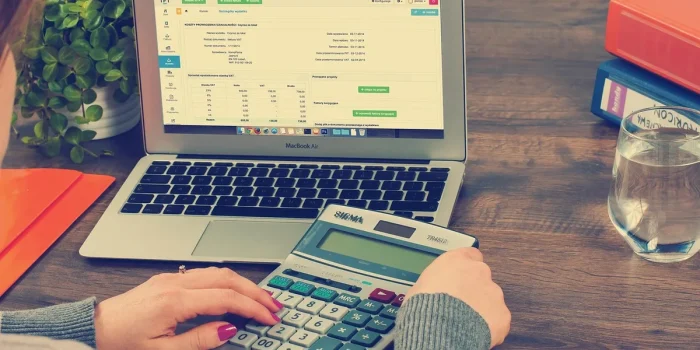 Mains anonymes triant des documents de prêt et une calculatrice sur une table baignée de lumière